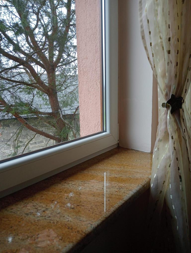 Jasny granit ozdabiający okno. Parapety granitowe Granmarys Jaworzno. Kamieniarz. Zakład kamieniarski